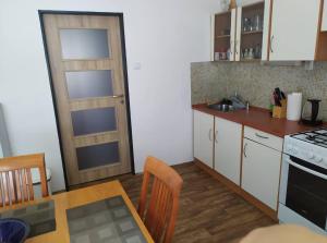 a kitchen with a table and a stove and a door at Apartmán Olomouc Nemilany in Olomouc