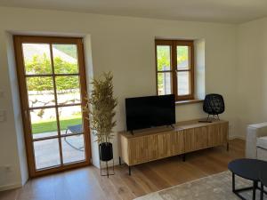 a living room with a flat screen tv on a wooden cabinet at Lichtdurchflutete Doppelhaushälfte in Kreuth in Kreuth