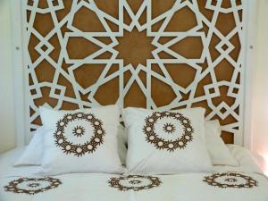 a bed with white pillows and a decorative headboard at Riad Darabi l Private Medina Home in Marrakesh