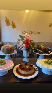 a table with cakes and a vase with flowers on it at Pousada da Leide in Fernando de Noronha