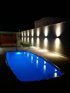 a blue swimming pool with lights on a building at casa inteira com 3 suites e área de lazer in Delfinópolis