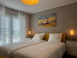 デ・コーフにあるTexelheerlijk 4のベッドルーム1室(ベッド1台付)が備わります。壁には絵画が飾られています。