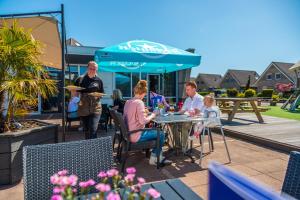 een groep mensen die aan een tafel op een patio zitten bij Europarcs Ijsselmeer in Medemblik