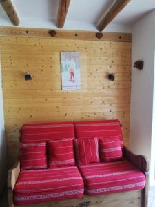 a red couch in a room with a wooden wall at GAUDISSARD A619 in Barcelonnette