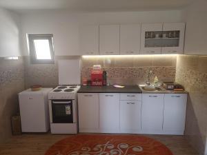 a small kitchen with white cabinets and a sink at Vila Bella Mia in Timotijevići