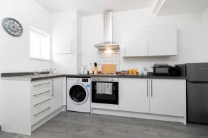 a kitchen with white cabinets and a washing machine at Modern and Pristine House near the Town Centre in Darlington