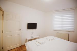 a bedroom with a white bed and a television at Apartman 4, Sinđelićeva 40 in Gornji Milanovac