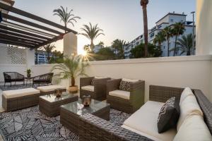een dakterras met banken, tafels en palmbomen bij MARBELLA BANUS SUITES - Daisy Playas del Duque Banús Beach Apartment in Marbella