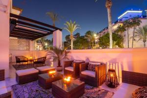 een patio met banken, tafels en palmbomen bij MARBELLA BANUS SUITES - Daisy Playas del Duque Banús Beach Apartment in Marbella