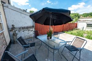 uma mesa e cadeiras com um guarda-sol num pátio em 4 bedrooms,2 bathrooms house with free parking em Plumstead