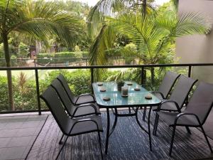 a table and chairs on a balcony with palm trees at Baden 84 Rainbow Shores Walk To Beach Resort Unit Pools Tennis Court in Rainbow Beach