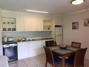 a kitchen with a table and a kitchen with white cabinets at Baden 84 Rainbow Shores Walk To Beach Resort Unit Pools Tennis Court in Rainbow Beach