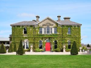 a house covered in ivy with a red door at Lyrath Estate in Kilkenny