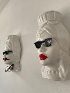 two masks of a woman with red lipstick and sunglasses at Macallè Suite Noto, charme e relax con giardino in Noto