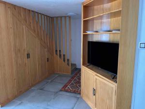 ein Wohnzimmer mit einem TV und Holzschränken in der Unterkunft Casa lele en anfi del mar in Los Caideros