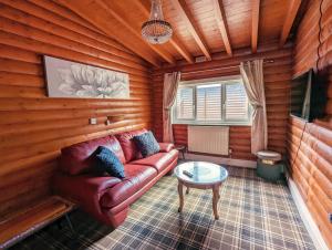 a living room with a red couch and a table at Kaoglen-Spruce-Hot Tub-Forrest Setting-Pet Friendly in Balnald