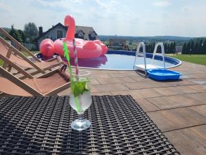 a drink on a table in front of a pool at Apartament POD STRZECHĄ in Bolmin