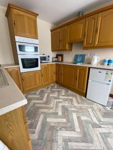 a kitchen with wooden cabinets and a patterned floor at The Coach House By The Sea in Mablethorpe