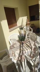 stół z 2 krzesłami i stół z kwiatami w obiekcie Casa Salento w mieście Novoli