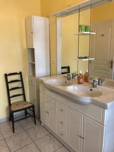 a bathroom with a sink and a chair and a mirror at La Verrerie de Guerlédan in Caurel