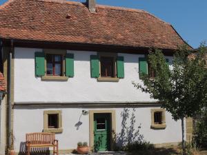 Casa blanca con persianas verdes y banco en Pilger- und Radlerherberge Herberge im Hofhaus, en Colmberg