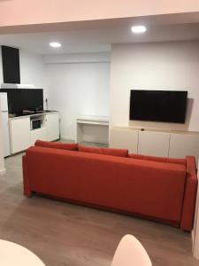 a living room with a red couch and a flat screen tv at Nest Flats Santiago VUT in Santiago de Compostela
