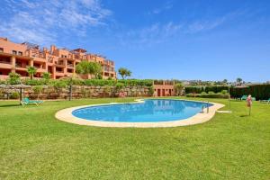 a swimming pool in the middle of a yard with a building at Estrella de Mar zeezicht en uitkijk op Gibraltar 40m2 terras incl zwembad Las Garzas Manilva in Manilva