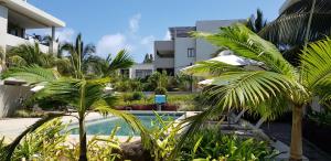 une piscine avec des palmiers en face d'un bâtiment dans l'établissement Beachwalk Deluxe Apartment - 50 steps to the beach, à Cap Malheureux