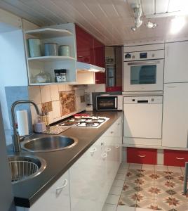 una cucina con armadi rossi e bianchi e un lavandino di Maison bord de Marne 8min disneyland et val d'Europe a Chalifert