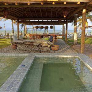 uma piscina em frente a um pavilhão na praia em Nuhatê Casa Hotel em Caraíva