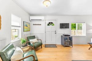 a living room with green chairs and a tv at The Cottage On Wilsonville Road in Wilsonville