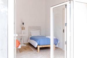 a bedroom with a bed with blue sheets and a mirror at Casa das Cegonhas in Vale de guiso