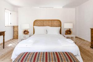 a bedroom with a large white bed with two tables at Casa das Cegonhas in Vale de guiso