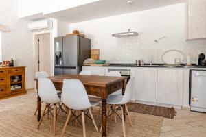 cocina con mesa de madera y sillas blancas en Casa das Cegonhas en Vale de guiso