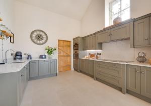 a kitchen with gray cabinets and a clock on the wall at Ynys Cadno in Trawsfynydd
