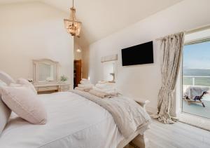 a white bedroom with a large bed and a window at Ynys Cadno in Trawsfynydd