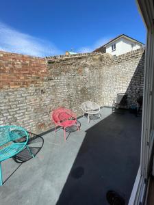 a patio with two chairs and a table and a brick wall at 3 bed apartment in London Plumstead in Woolwich