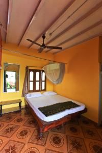 un letto in una camera con pareti gialle e soffitto di Archana Guest House River View a Hampi
