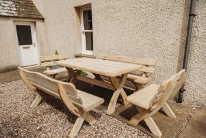 einem Picknicktisch aus Holz und Stühlen neben einem Gebäude in der Unterkunft The Herdsman's House in Thurso