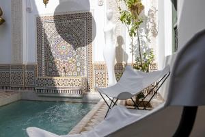 uma piscina com duas cadeiras e uma parede de mosaico em Riad LAZ Mimoun & Spa em Marrakech