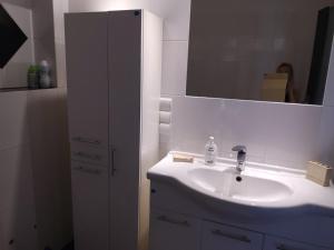 a white bathroom with a sink and a mirror at Juvenka in Dziwnówek