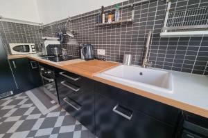 a kitchen with a white sink and black tiles at The zenitude of Shepherds #DO in Grenoble