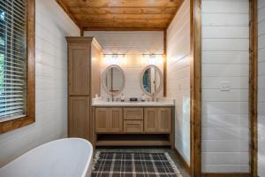 a bathroom with a tub and a sink and mirrors at Blissful Pines in Broken Bow