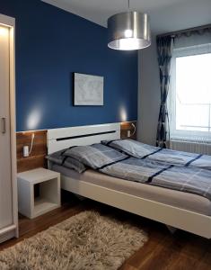 - une chambre avec un lit et un mur bleu dans l'établissement Lively Debrecen, à Debrecen