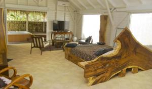 1 dormitorio con 1 cama grande de madera y TV en Villa Dream, en Deshaies