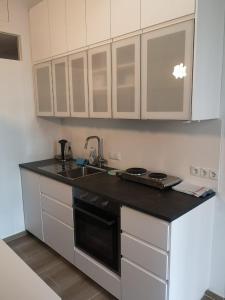 a kitchen with white cabinets and a black counter top at Ruhige Art-Garconniere mit Balkon in Vienna