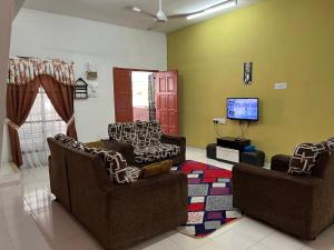 a living room with two chairs and a tv at Homestay D-Zara in Ipoh