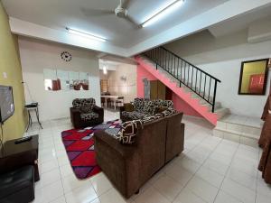 a living room with two couches and a staircase at Homestay D-Zara in Ipoh