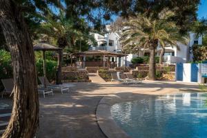 a resort with a swimming pool and palm trees at Alua Suites Las Rocas in Cala d´Or