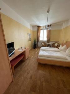 1 dormitorio con 2 camas, escritorio y TV en zum Schwanen Garni, en Buggingen